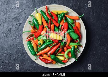 Colori diversi peperoncini nel piatto in legno Foto Stock