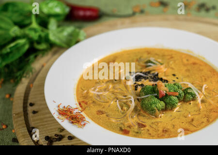 Minestra con broccoli, spaghetti di riso e verdure su un supporto di legno Foto Stock
