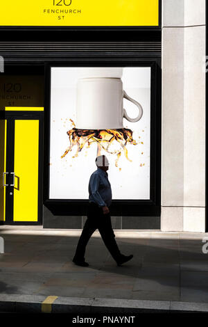 UK,città di Londra,UK-uomo cammina lungo un cartellone di visualizzazione di un upside-down tazza di caffè. Foto Stock