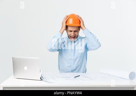 Concentrati gravi operosi ingegnere occupato a lavorare sul grande progetto di architettura tardo, seduto alla sua area di lavoro utilizzando digital tablet pc. Persone, lavoro, occupazione e professione concetto Foto Stock