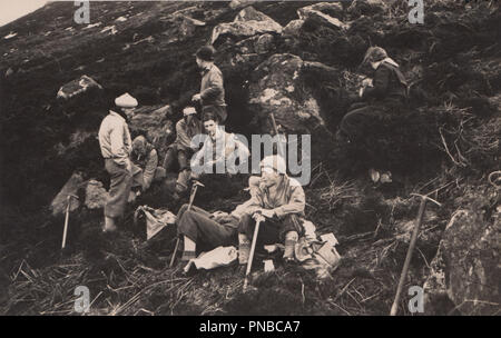 * Vintage Fotografia di alpinisti o Hill Walkers prendendo una pausa sul pendio a monte. Foto Stock