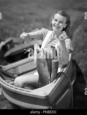 1940s sorridente giovane donna seduta in barca a remi guardando la fotocamera mantenendo la bella cattura di pesce - Una2809 DEB001 HARS CELEBRAZIONE FEMMINE ORGOGLIOSO CASA RURALE LIFE natura copia di cattura dello spazio a mezza lunghezza LADIES PERSONE ESPRESSIONI ATLETICO B&W contatto visivo cattura il successo di Nizza felicità allegro elevato angolo avventura LEISURE forza emozione ricreazione orgoglio nel fino sorride gioiosa elegante DEB001 mostra il relax WILDLIFE giovane donna adulta in bianco e nero di etnia caucasica in vecchio stile Foto Stock