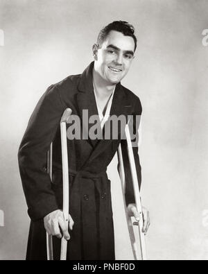 1940s uomo sorridente guardando la telecamera indossare accappatoio a camminare sulle stampelle - un3948 HAR001 HARS ISPIRAZIONE NEGLI STATI UNITI D'AMERICA MASCHI AILMENT FIDUCIA B&W contatto visivo avvolto sofferenza allegro sorriso di recupero feriti recuperando le cattive condizioni di salute malata MID-adulto metà uomo adulto BIANCO E NERO ETNIA CAUCASICA HAR001 VECCHIO POST GUERRA Foto Stock