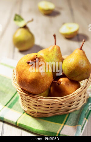 Pere fresche nel cesto di vimini sulla tavola di legno Foto Stock