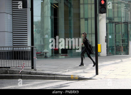 Elegante giovane donna vestita di nero a piedi lungo Finsbury Pavement al di fuori di un edificio aziendale nella città di Londra Foto Stock