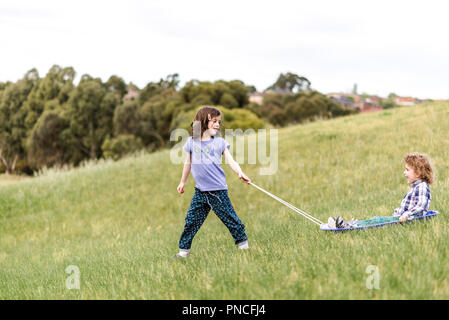 Bambini erba slittino sulla pista da slittino una discesa da una collina in un parco Foto Stock