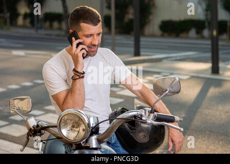 Uomo con gli scooter parla al telefono sulla città Foto Stock