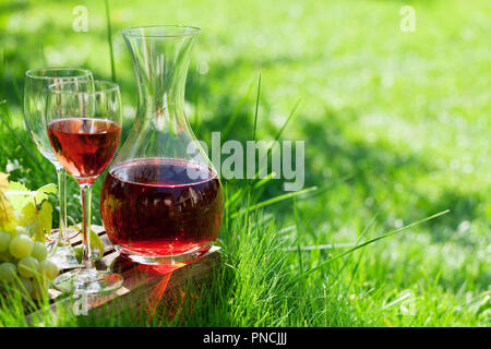 Vino rosato nel decanter e bicchieri e uva. All'aperto in vigna. Con spazio per il testo Foto Stock