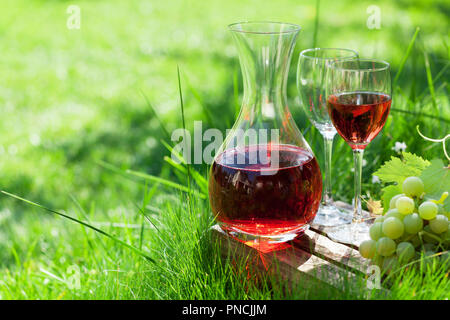 Vino rosato nel decanter e bicchieri e uva. All'aperto in vigna. Con spazio per il testo Foto Stock