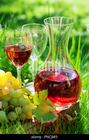 Vino rosato nel decanter e bicchieri e uva. Outdoor in vigna Foto Stock