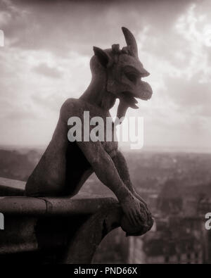 1920s la CATTEDRALE DI NOTRE DAME GARGOYLE di pietra di chimera che si affaccia sullo skyline di Parigi Francia - r4364 HAR001 HARS MONSTER ZANY UNCONVENTIONAL CORNUTO Duomo scolpita ancora vita elegante elemento GARGOYLE IDIOSINCRATICA simbolica creatività divertente creatura demoniaca formata eccentrico grottesche mostruoso affacciato sulla linguetta sporgente alato di nero e di bianco fantasia irregolare HAR001 mitica cattedrale di Notre Dame in vecchio stile nave Foto Stock