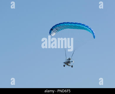 Powered parapendio volando sotto il cielo blu chiaro Foto Stock