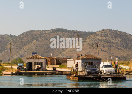 Butrinto, Albania- 29 giugno 2014: Automobili traversata in traghetto attraverso il lago di Butrinto. Montagna in background. Foto Stock