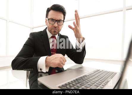 Imprenditore serio controllo conti mentre è seduto alla sua scrivania Foto Stock