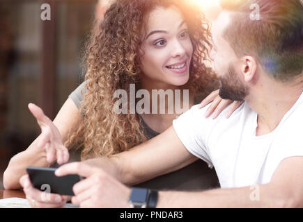 Felice coppia utilizzando uno smartphone seduti in terrazza Foto Stock