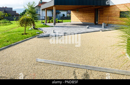 La posa di cemento grigio Pavimentazioni in casa cortile carraio patio. I lavoratori professionali di muratori sta installando nuove piastrelle o lastre per passo carraio, Foto Stock