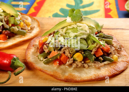 Croccante di carni bovine tostada stack, tipica cucina messicana, fatta con fritti e croccanti tortillas di mais con guacamole, formaggio, panna acida e salsa Foto Stock