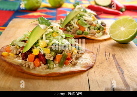 Croccante di carni bovine tostada stack, tipica cucina messicana, fatta con fritti e croccanti tortillas di mais con guacamole, formaggio, panna acida e salsa Foto Stock