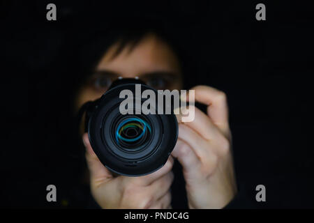 Il fotografo guarda la telecamera su uno sfondo nero Foto Stock