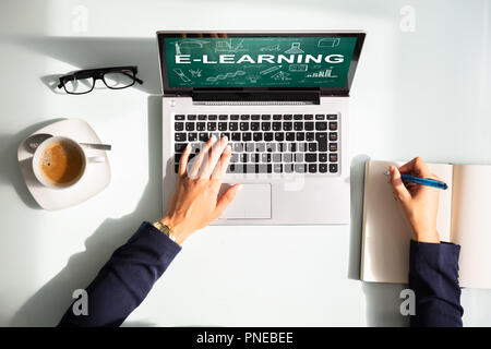 Vista in elevazione del imprenditrice la mano con il computer portatile che mostra l'E-learning concetto sullo schermo Foto Stock