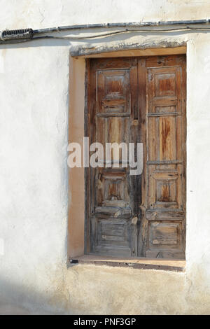 Un restaurato a due facciate porta marrone in un bianco e pareti beige con alcuni cavi che passa su di essa nel Almonacid de la Cuba paese rurale città in Spagna Foto Stock