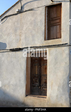 Un restaurato a due facciate porta marrone in un bianco e pareti beige con alcuni cavi che passa su di essa nel Almonacid de la Cuba paese rurale città in Spagna Foto Stock