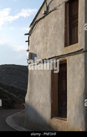 Un restaurato a due facciate porta marrone in un bianco e pareti beige con alcuni cavi che passa su di essa nel Almonacid de la Cuba paese rurale città in Spagna Foto Stock