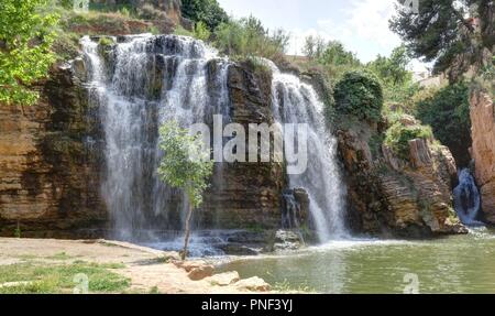 Un paesaggio del fiume Huerva rock cascate doppia circondata da verdi alberi e cespugli nel parco Muel durante la primavera, Spagna Foto Stock