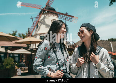 Due belle sorelle ridere gli uni con gli altri mentre per scattare delle foto e di visitare una città bellissima. Foto Stock