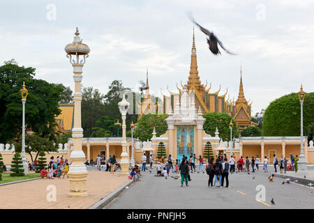 Pedoni godendo la sera presto di fronte al cancello principale del Palazzo Reale complesso in Phnom Penh Cambogia. Le guglie dorate del trono H Foto Stock