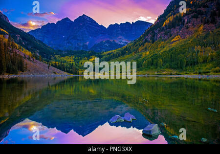 Epic picchi di montagna durante il tramonto e cieli colorati riflettono in placido lago in autunno. Foto Stock