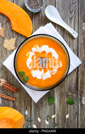 Delicato purea di zucca con panna e chia semi in un nero ciotola di vetro su di un tavolo di legno. Vista dall'alto. Foto Stock