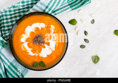 Delicato purea di zucca con panna e chia semi in un nero ciotola di vetro su uno sfondo luminoso. Vista dall'alto. Foto Stock