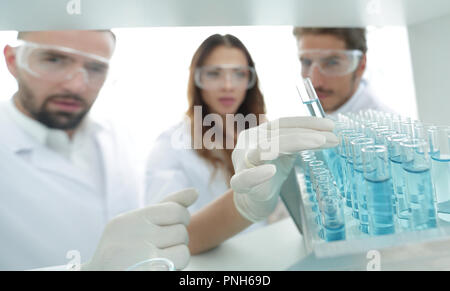 Immagine di sfondo è un gruppo di scienziati che studiano il liquido nel tubo di vetro. Foto Stock