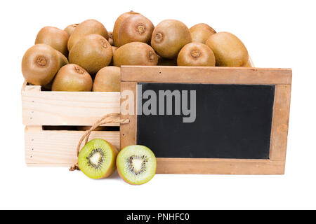 Scatola di legno riempita con molti mature kiwi e due metà di frutta e una vecchia ardesia vuoto blackboard isolati su sfondo bianco Foto Stock