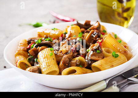 Pasta Vegetariana rigatoni con funghi e peperoncino in vaso bianco sulla tabella grigia. Cibo vegan. Foto Stock