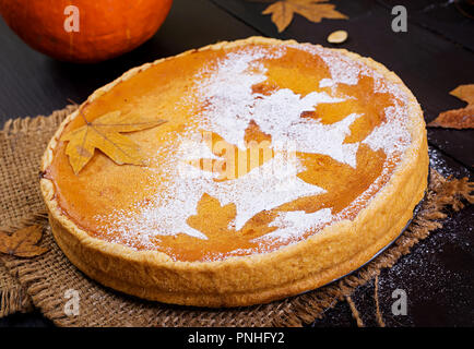 American fatti in casa torta di zucca con cannella e noce moscata, semi di zucca e foglie di autunno su un tavolo di legno. Il cibo del ringraziamento. Foto Stock