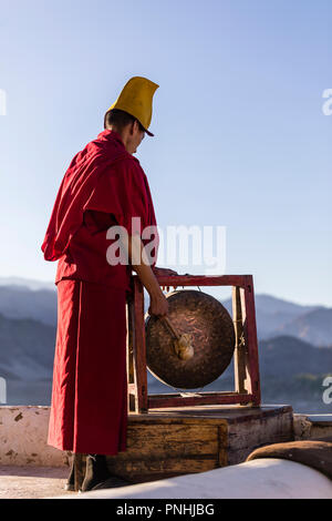 Un monaco suona il gong campana al monastero di Thiksey in Ladakh regione dell India Foto Stock