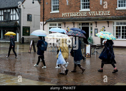 Turisti stranieri in condizioni di bagnato che porta ombrelli, Stratford-upon-Avon, Warwickshire, Regno Unito Foto Stock