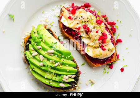 Sandwich sano sulla patata dolce per la prima colazione o uno spuntino. Un toast con avocado e altri con lampone chia marmellata, burro di arachidi e banana con supe Foto Stock