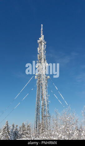 Coperto di neve e la torre della TV contro il cielo blu Foto Stock