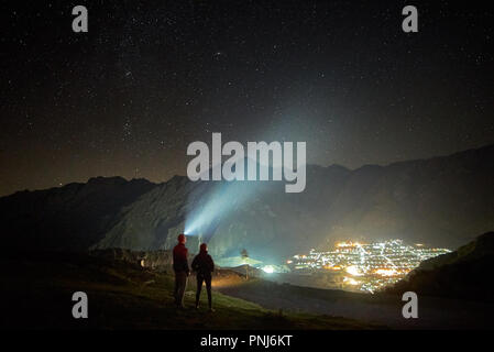 Coppia felice escursionisti sotto il cielo notturno e le luci della città a sfondo Foto Stock