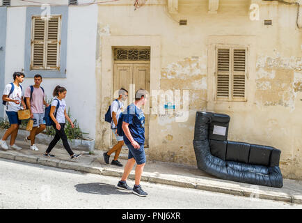 In disuso in pelle nera angolo sedia messo sul pavimento in Sliema Malta pronta per essere raccolti. Foto Stock