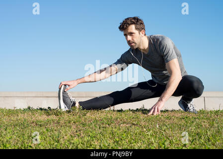 L uomo si allunga la gamba nel terreno Foto Stock