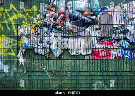 Vari articoli di imballaggio scartati intrappolata dietro una maglia a filo. Foto Stock