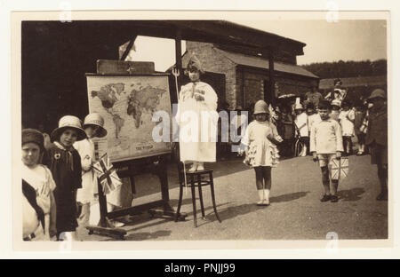 Cartolina di Strood scuola di pace per bambini Fete, Strood, Rochester, Kent, Regno Unito Un bambino è vestito in un costume Brittania e lei è in piedi accanto a Philips mappa del mondo.La cartolina è datata 4 agosto 1919, Foto Stock
