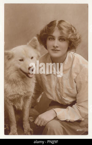 Cartolina di auguri di colore seppia originale dei primi anni '1900 della bella giovane attrice Peggy Kurton con un cane Samoyed, circa 1916, Regno Unito Foto Stock