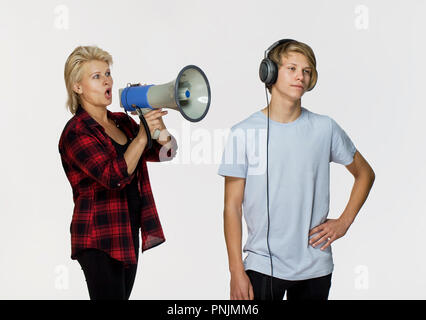 Le incomprensioni in famiglia. Arrabbiato madre con megafono a parlare con il suo maschio adolescente Foto Stock