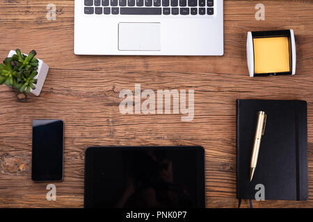 Vista aerea di forniture per ufficio e gadget elettronici sulla scrivania in legno Foto Stock