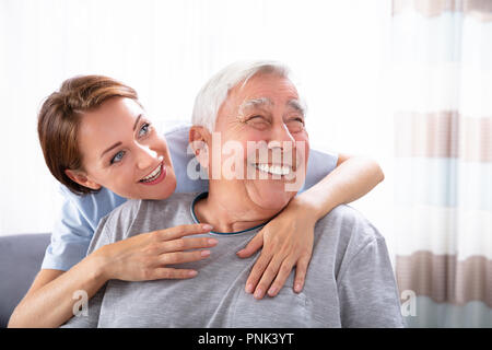 Close-up di un felice infermiera femmina rivolta a qualcosa di uomo Senior Foto Stock